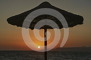 Beach umbrella at sunset with setting sun photo