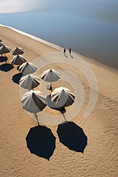 beach umbrellas casting shadows on the sand near water