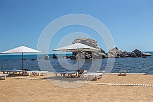 Beach umbrellas and deck chairs on the beach near the cliff