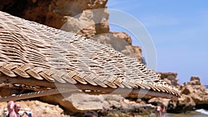 Beach with umbrellas in Egypt on Red Sea. Sunny resort on rocky coast.