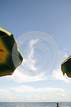 Beach umbrellas on the foreshore with people bathing in the sea. Concept.