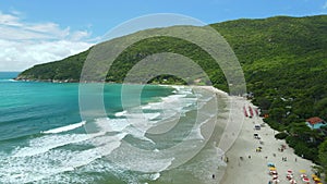 Beach with umbrellas and ocean with waves in Santa Catarina, Floripa. Aerial view