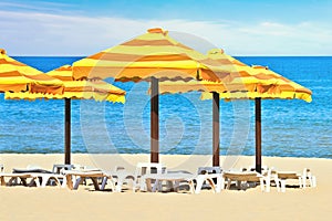 Beach umbrellas and sunbath seats on sand beach photo