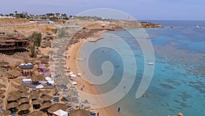 Beach with umbrellas and sunbeds at the luxury hotel on red sea near the coral reef. Egypt.