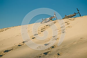 on the beach under a blue sky on the sand are two bicycles, a sunny summer day