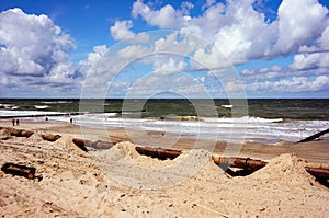 Beach in Ustronie Morskie resort in Poland, a big rusty pipe on the sandy beach in the foreground