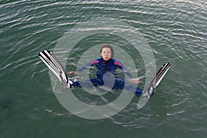 Beach vacation fun woman wearing a wetsuit and flippers making a goofy face while swimming in ocean water