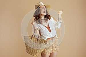 happy elegant woman in blouse and shorts rejoicing on beige photo