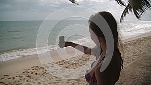 Beach vacation people - woman white bathing suit makes selfie relaxing looking at perfect paradise asian sea . Girl in