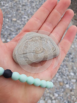 Beach vibes. Hand holding weathered stone with cool layers