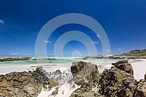 Beach view with white sand, rocks and crystal clear water at Brandfontein - Rietfontein Nature Reserve near Cape Agulhas