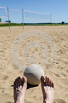 Beach volleyball with blue sky and net and feet