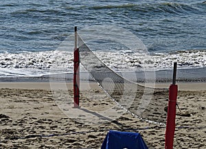 Beach volleyball court on the sandy shore near the sea. No one at the site. Sea view, sea waves, sunny day, windy weather