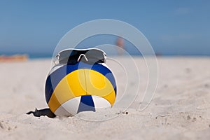 Beach Volleyball. Game ball with glasses on top under sunlight blue sky on sand