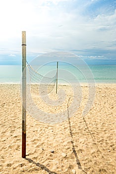 Beach volleyball net on a golden sand beach with turquoise sea waters and bright blue sunny sky