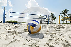 A beach volleyball net on a sunny beach, with palm trees