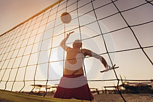 Beach volleyball player in action on the sand beach in sunset.