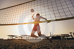 Beach volleyball player in action on the sand beach in sunset.