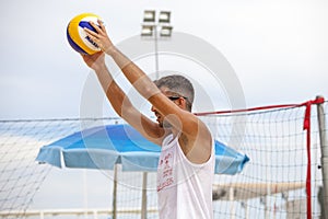 Beach volleyball player and ball game arms stretched out in front.