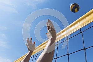 Beach volleyball woman player in action at sunny day under blue sky . hands close-up reach for ball
