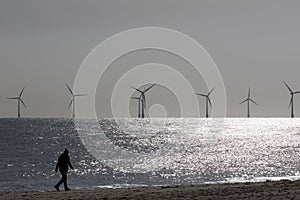 Beach walk. Morning coronavirus lockdown isolation exercise by wind turbines