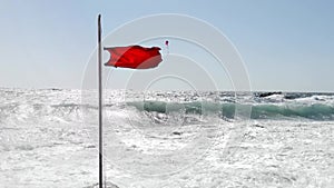 Beach warning red flag splashing on wind.