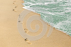 Beach, wave and footprints on sand. Vacation concept. Time, life passing