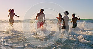 Beach, wave and friends playing in ocean together for fun on travel, vacation or holiday in summer. Splash, back and