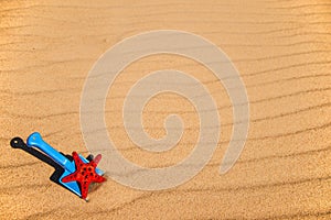 Beach with kid toys shovel, bucket and red sea star