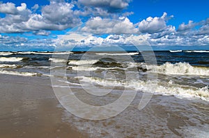 Beach with waves and clouds on a blue sky