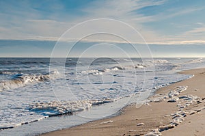 Beach with waves and spume with blue sea and sky