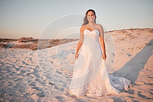 Beach wedding, bride and happy woman in a white dress while standing in sand and sun enjoying her special day at a