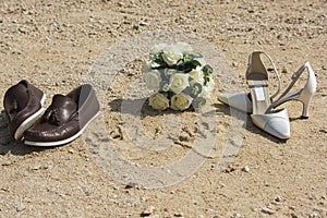Beach wedding concept with shoes and rings in sand