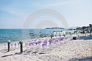 Beach wedding venue settings with white chiavari chairs decorate with purple organza sash at seaside