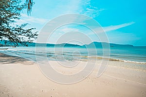 beach, white sand, blue ocean water and lush green tropical jungle, small green islands on horizon