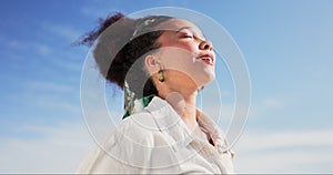 Beach, wind and happy woman breathing in nature for travel, freedom and adventure on blue sky background. Ocean, face