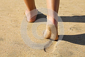 Beach woman legs feet walking barefoot on sand leaving footprints on golden sand in sunset. Vacation travel freedom people