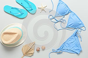 Beach womens accessories on a gray pastel background. Bikini swimsuit, hat, flip flops. Top view, flat lay
