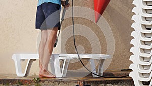 Beach worker washes the beach loungers deck chairs with a jet of water.