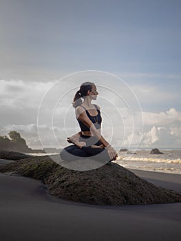 Beach yoga. Asian woman practicing Parivrtta Sukhasana outdoor. Sitting in variation of Lotus pose. Easy twist pose. Stretching