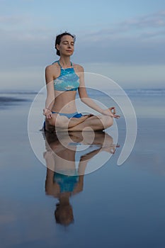 Beach yoga practice in Bali. Lotus pose. Padmasana. Hands in gyan mudra. Meditation and concentration. Zen life. Relaxation of