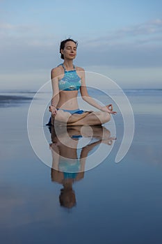 Beach yoga practice in Bali. Lotus pose. Padmasana. Hands in gyan mudra. Meditation and concentration. Zen life. Relaxation of