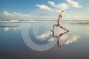 Beach yoga. Slim Caucasian woman practicing Virabhadrasana II, Warrior II Pose. Strong body. Healthy lifestyle. Water reflection.