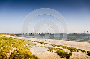 Beach in Zeeland and the famous flood barrier Oosterscheldekering of the Delta works in the background on a sunny summer day. The
