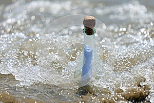 beached bottle with secret message inside and waves of sea