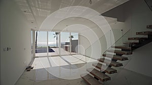 Beachfront villa interior showcases open space, modern design, floating staircase, panoramic ocean views,, luxury