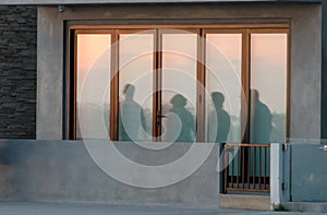 Beachgoers reflections at windows of a beach house