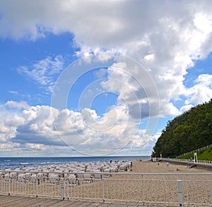 Beachlife at stormy weather with pier, sand, beach chairs and blue and cloudy sky on the island Ruegen