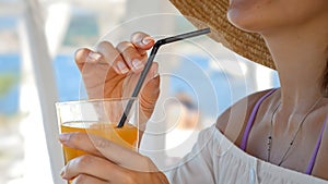 At a beachside cafe, a woman drinks orange juice, symbolizing summer holidays and coastal relaxation