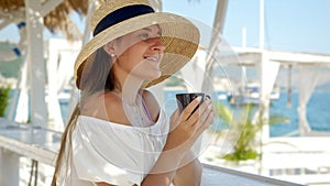 At a beachside cafe, a woman enjoys coffee, symbolizing summer holidays and coastal relaxation